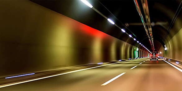 Osvetlený tunel s prechádzajúcim autom