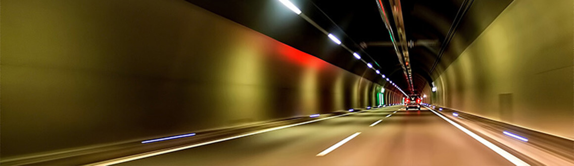 Osvetlený tunel s prechádzajúcim autom