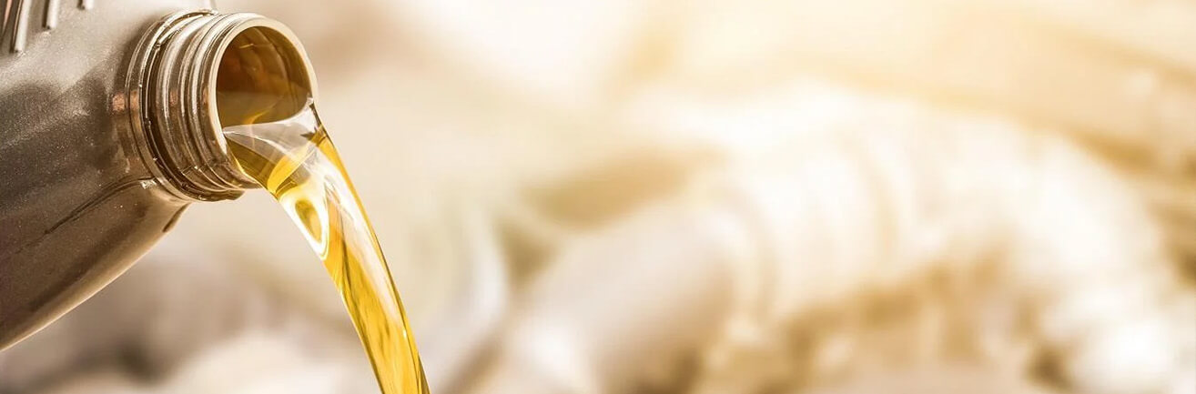 Detail hrdla balenia oleja na zlatom pozadí, z ktorého je nalievaný olej