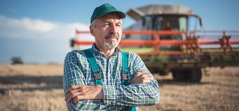 Poľnohospodár stojí na poli s kombajnom v pozadí