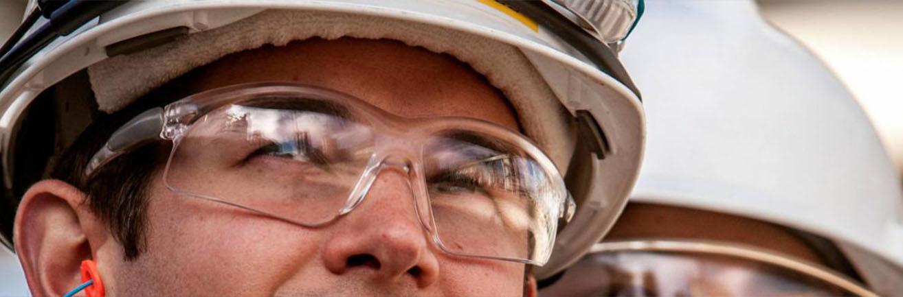 Detail pracovníka TotalEnergies s ochrannými okuliarmi a helmou